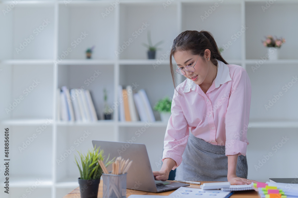 Sharing good business news. Attractive young businesswoman Used the laptop with document and smiling while sitting at her working place in office. Sharing good business news. Attractive young businesswoman Used the laptop with document and smiling while sitting at her working place in office.