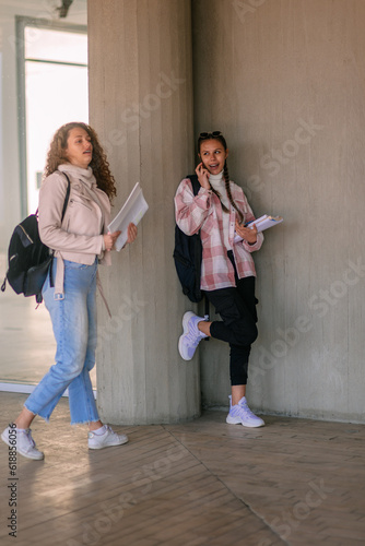 School girl having phone call while her friend is passing next to her