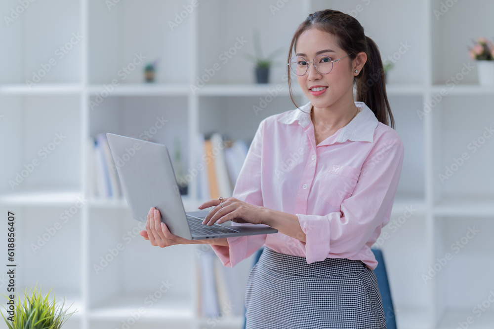 Sharing good business news. Attractive young businesswoman Used the laptop with document and smiling while sitting at her working place in office. Sharing good business news. Attractive young businesswoman Used the laptop with document and smiling while sitting at her working place in office.