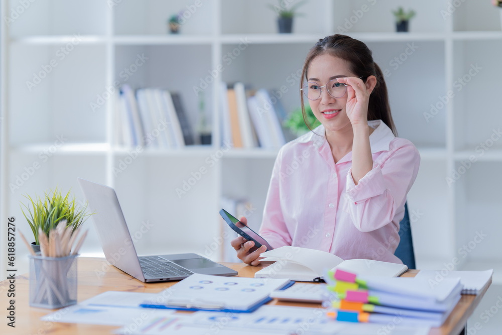 Image of smiling beautiful woman writing down notes while sitting at table in office Image of smiling beautiful woman writing down notes while sitting at table in office