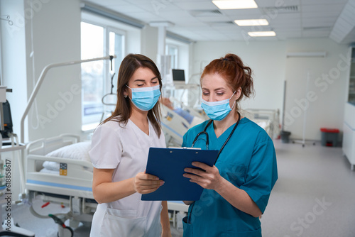Female medics with clipboard talking with each other in clinic