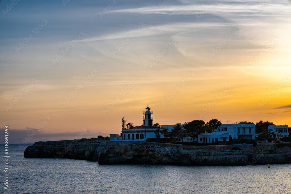 Landscape view of Cala Santandria with lighthouse at sunset Menorca, Spain.