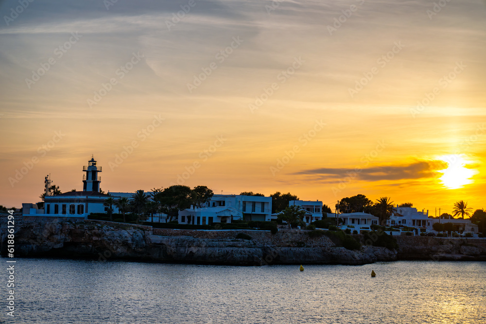Landscape view of Cala Santandria with lighthouse at sunset Menorca, Spain.