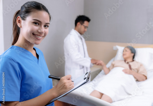 Elderly Asian woman is being treated at a hospital under close supervision of doctors and nurses.