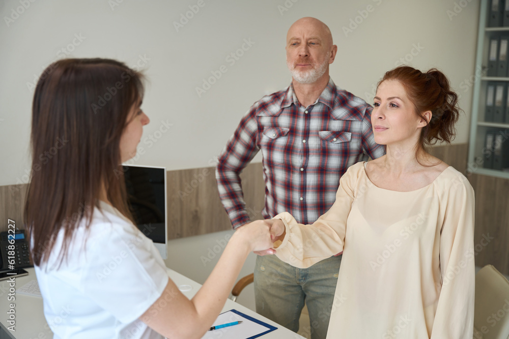 Fototapeta premium Partners shaking hands with female gynecologist in clinic