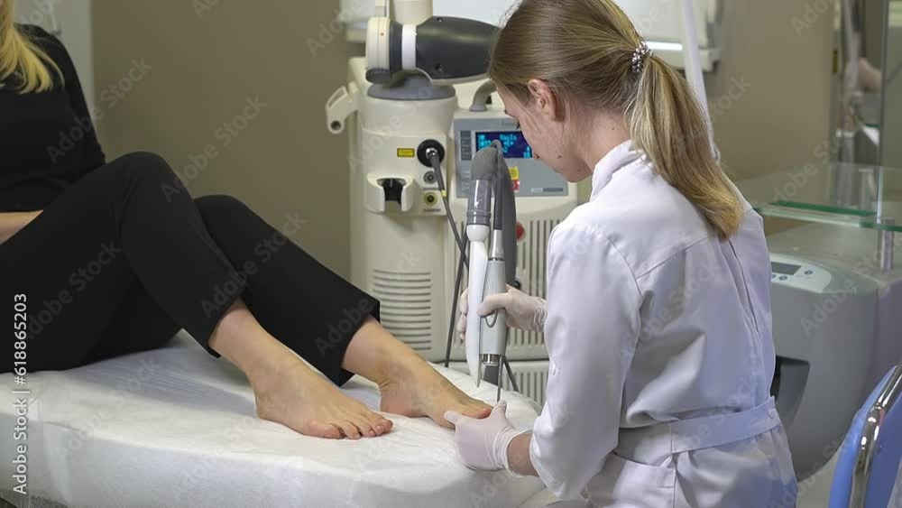 Woman doctor doing laser treatment procedure for toenail fungus. Fungal