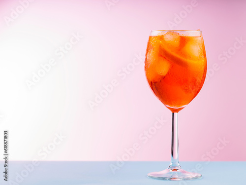 Cocktail Aperol Spritz with orange slice and ice cubes. Aperol Spritz cocktail in glass on a pink blue background. Copy space