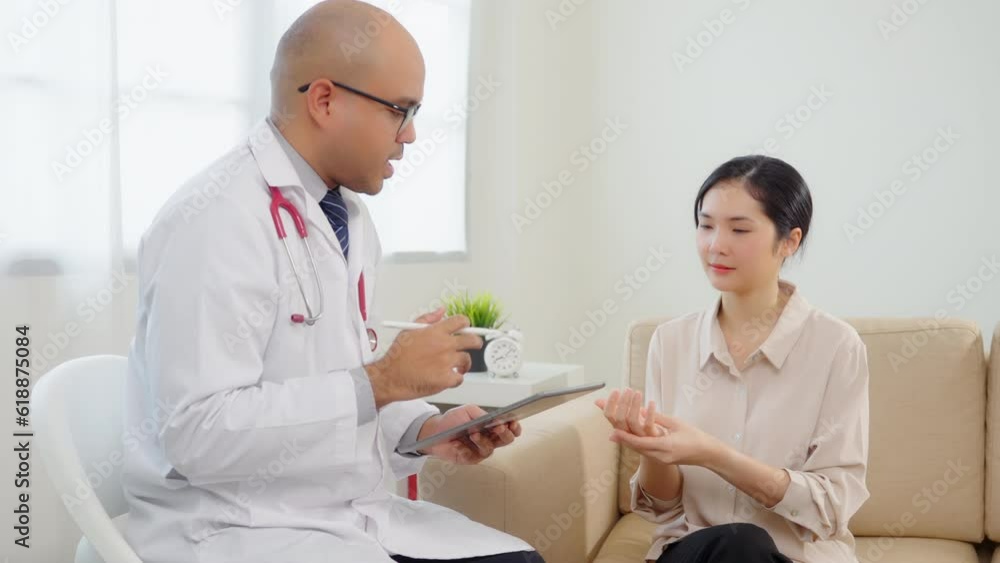 Beautiful asian women patient hurt hand consulting with Handsome asian professional doctor about pain in her hand feeling suffering and The doctor writing and analyzing her symptoms on the tablet. Beautiful asian women patient hurt hand consulting with Handsome asian professional doctor about pain in her hand feeling suffering and The doctor writing and analyzing her symptoms on the tablet.