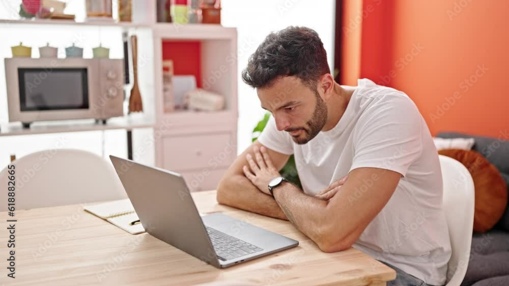 Young hispanic man using laptop sitting on table at dinning room Young hispanic man using laptop sitting on table at dinning room