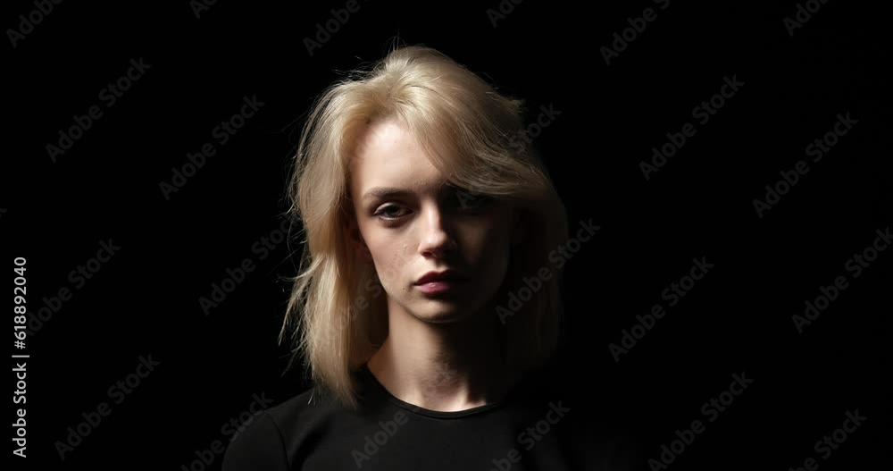 A serious Caucasian woman as she stands against a captivating black background, locked in a powerful gaze directed right at the camera. With a compelling expression etched upon her face. A serious Caucasian woman as she stands against a captivating black background, locked in a powerful gaze directed right at the camera. With a compelling expression etched upon her face.
