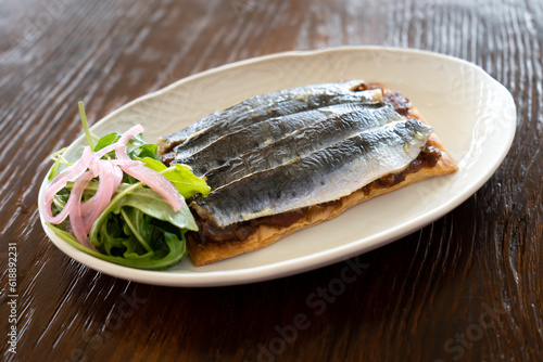 Studio photo of a plate of sardines on toast with salad, gourmet style