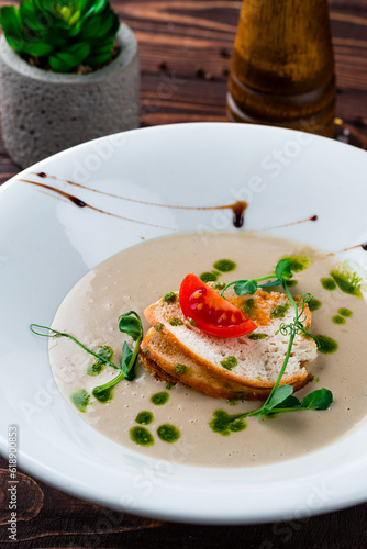 Champignon cream soup with cherry tomatoes, microgreens and croutons, vegetarian food.