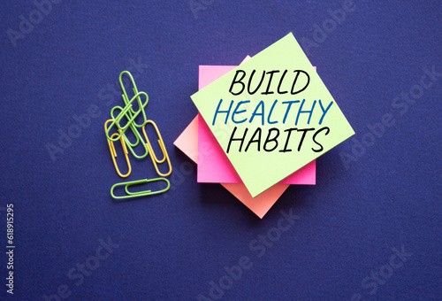 Healthy habits symbol. Concept word Build Healthy habits on yellow stealy note with paper clips. Beautiful deep blue background. Healthy lifestyle and Healthy habits concept. Copy space photo