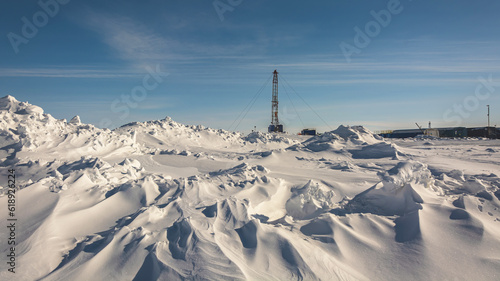 The Northern gas field. There is a lot of snow in the foreground. In the background is a mobile installation for well repair. A frosty winter day. Sunny blue sky © mangz