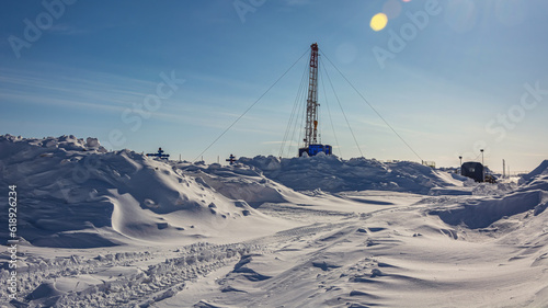 The Northern gas field. There is a lot of snow in the foreground. In the background is a mobile installation for well repair. A frosty winter day. Sunny blue sky © mangz