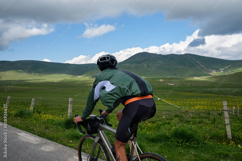 Cyclist training in the mountains on a road bike with a beautiful view of Bucegi Mountains. Cycling holiday in Romania. 