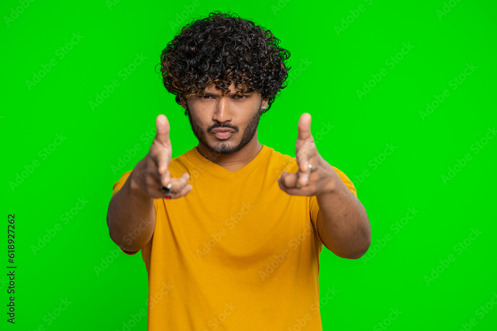Happy young indian man pointing around with finger gun gesture, looking confident, making choice, shooting killing with hand pistol right on target. Hindu guy isolated on green chroma key background Happy young indian man pointing around with finger gun gesture, looking confident, making choice, shooting killing with hand pistol right on target. Hindu guy isolated on green chroma key background
