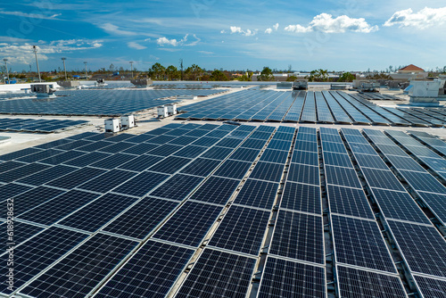 Aerial view of blue photovoltaic solar panels mounted on industrial building roof for producing clean ecological electricity. Production of renewable energy concept