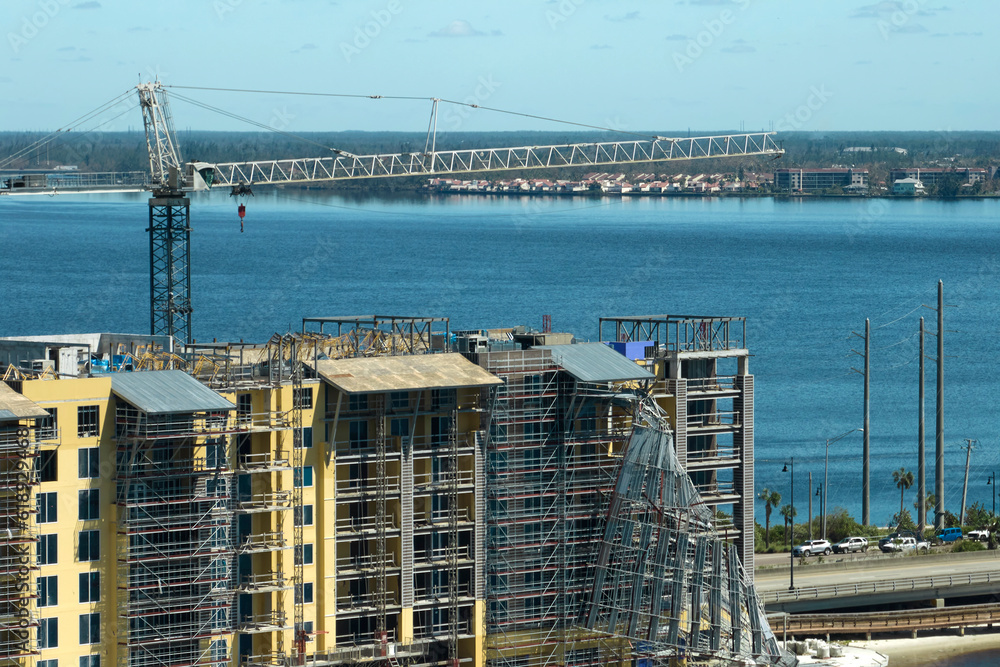 Aerial view of ruined by hurricane Ian construction scaffolding on high apartment building site in Port Charlotte, USA