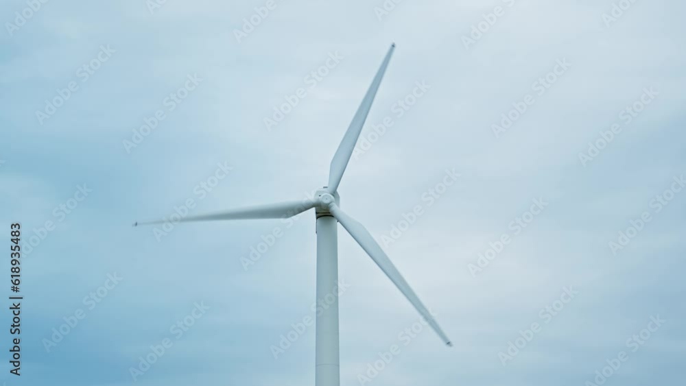 Windmill. Green energy concept. Wind power turbine generating clean renewable energy. Central composition. Clouds at background. 4K, UHD Windmill. Green energy concept. Wind power turbine generating clean renewable energy. Central composition. Clouds at background. 4K, UHD