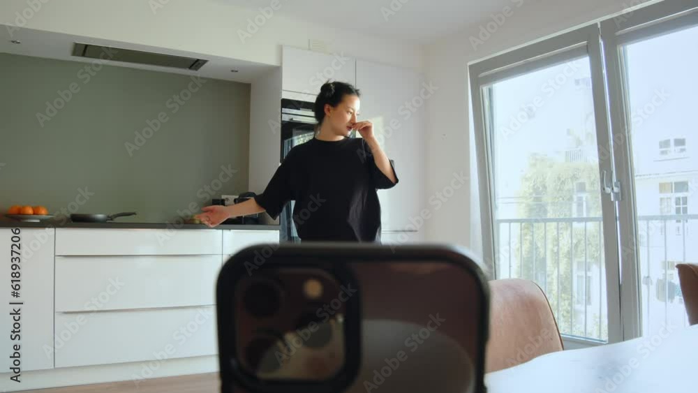 Serious teen girl putting mobile phone at the glass and talking with her subscribers Serious teen girl putting mobile phone at the glass and talking with her subscribers