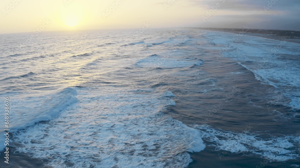 Sunset over ocean waves, flying over the sea during golden hour. Giant waves foaming and splashing in the sea. Drone, sunset wavy seascape. Ocean and sky background landscape 