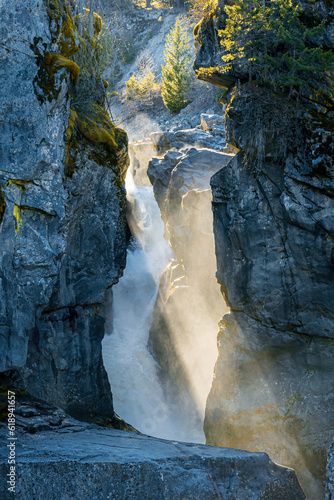 Light rays shining through a ravine and a waterfall