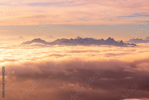 Orange sunset with mountain peaks above clouds