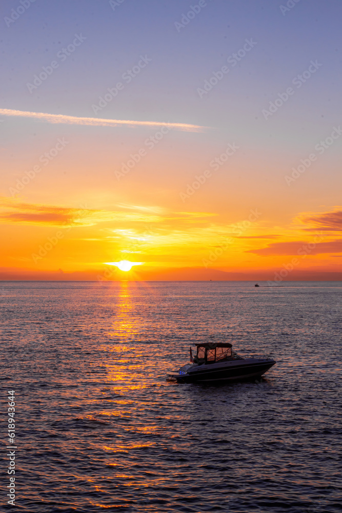Orange sunset with ocean and a boat