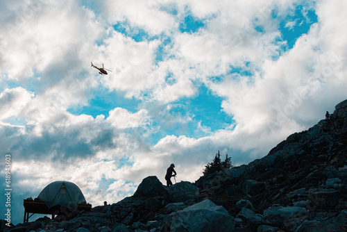 Helicopter flying above a man camping on a hill