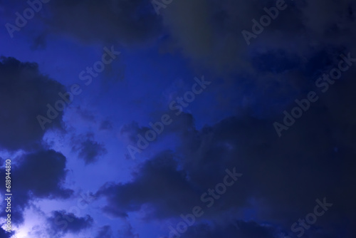 Flashes of light from the approaching storm illuminate the clouds in the night.