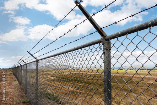 Εκτύπωση καμβά A long chain link fence with barbed wire stretches into istance