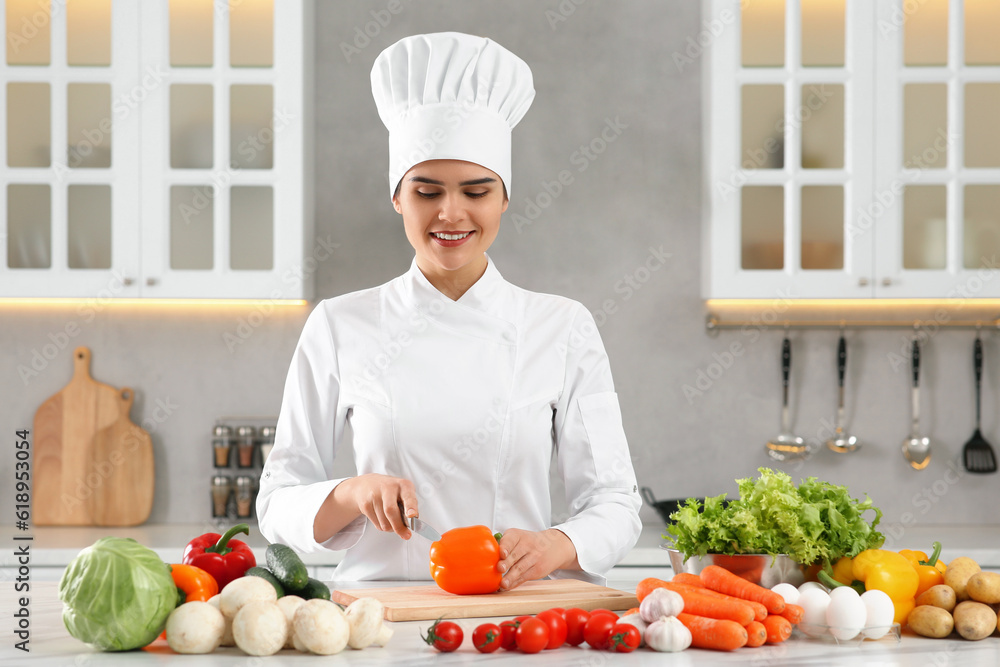 Professional chef cutting cut bell pepper at white marble table in kitchen Professional chef cutting cut bell pepper at white marble table in kitchen