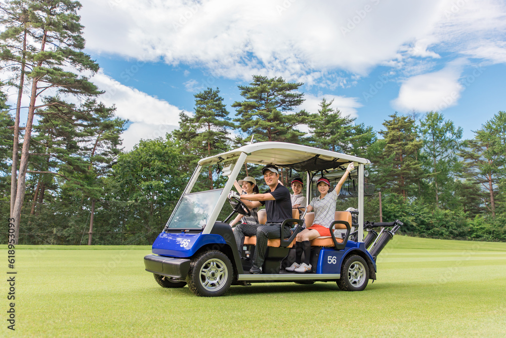 ゴルフ場でゴルフカートに乗るゴルファーの男女
