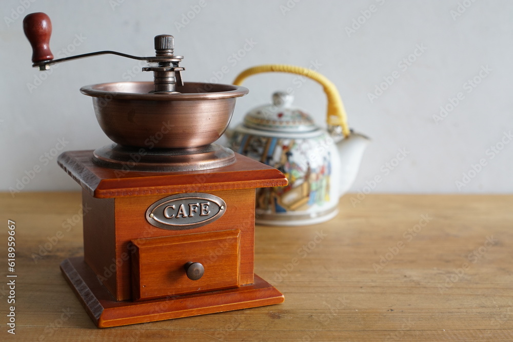 Vintage manual coffee grinder and ceramic traditional chinese tea pot, coffee versus tea comparison
