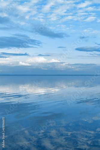 Nature picturesque landscape, clouds reflected on water surface, windless summer weather, tranquil blue trend sky background, mirroring sky on water, white blue nature gradient, aesthetic
