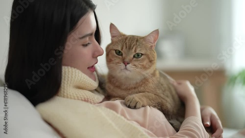 Cheerful woman in casual clothes spending her free time on vacation playing with cute pet at home.