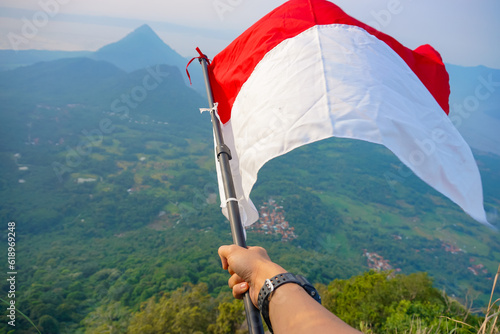hand holding Indonesia flag on blue sky background with nature view Indonesia independence day, National holiday Day and happy celebration concepts