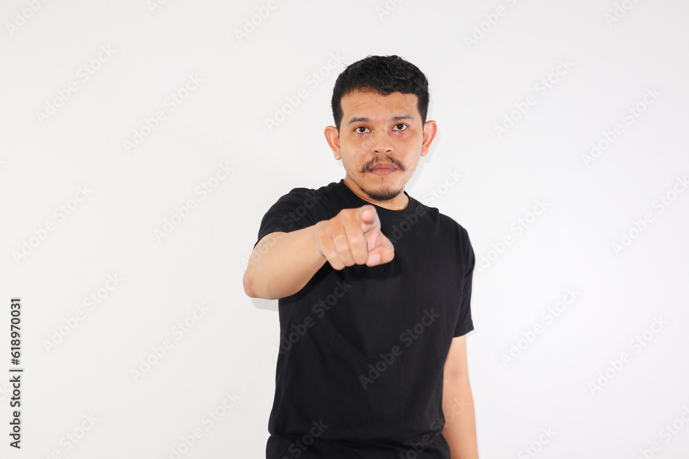 Adult Asian man pointing forward and showing glaring face expression, isolated in white background Adult Asian man pointing forward and showing glaring face expression, isolated in white background