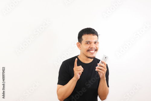 Adult Asian man looking to camera while holding his mobile phone with happy expression photo