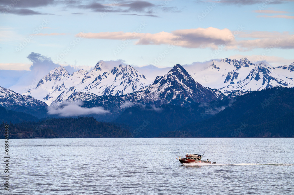 Fishing boat returning home to Katchemak Bay in the evening, mountain range in the background, Homer, AK

