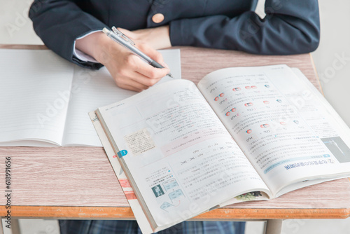 学校の教室で化学の教科書・参考書を見ながら勉強する女子高校生・中学生の生徒
 photo