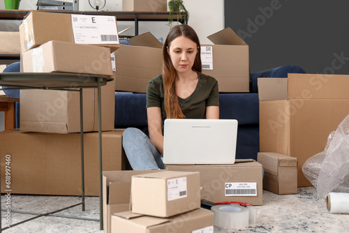 Young woman with parcels using laptop at home © Pixel-Shot
