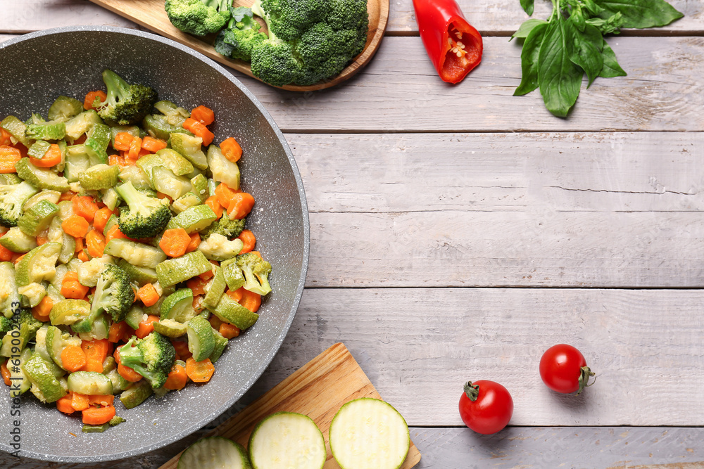 Frying pan with different vegetables on grey wooden background Frying pan with different vegetables on grey wooden background
