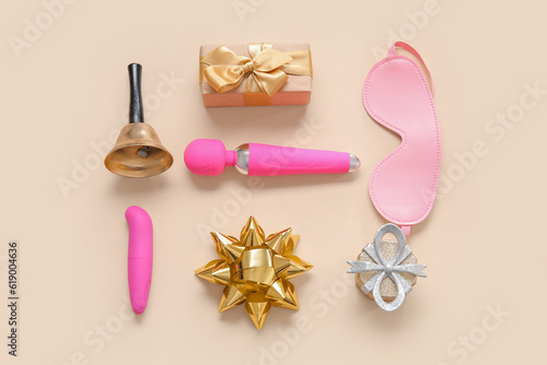 Gift boxes with vibrators, bell and mask on beige background