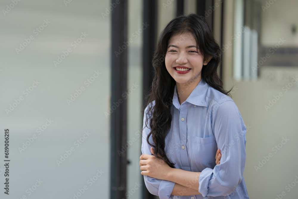 Beautiful Asian businesswoman standing with her arms crossed and looking at the camera smiling and laughing happily.