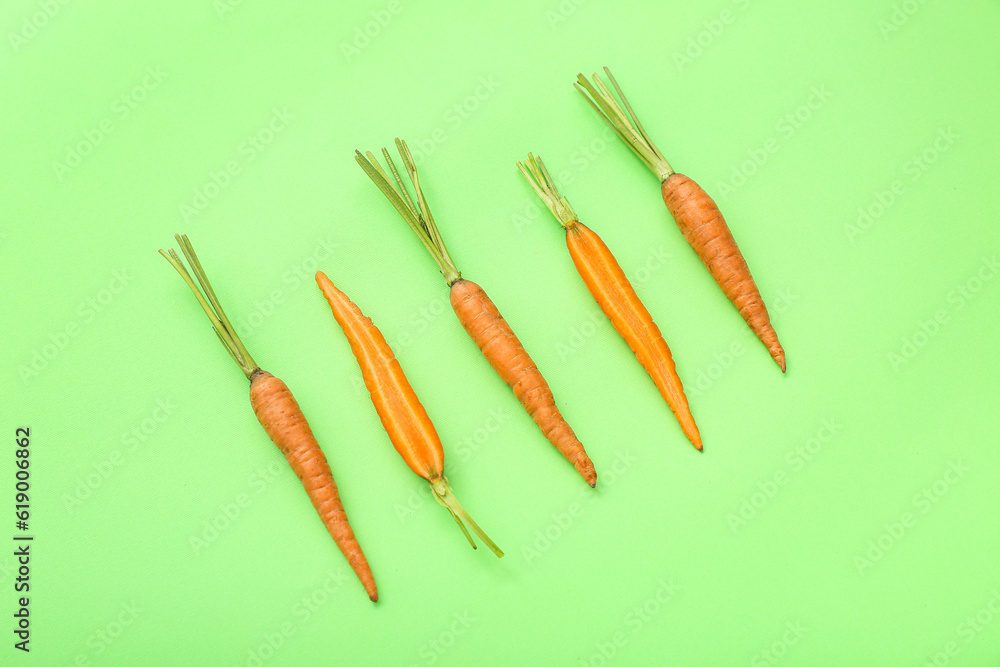 Fresh carrots and halves on green background Fresh carrots and halves on green background