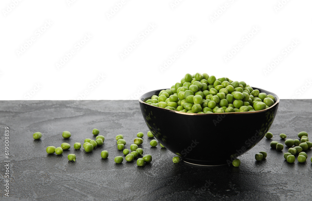 Bowl with fresh green peas on black table against white background Bowl with fresh green peas on black table against white background