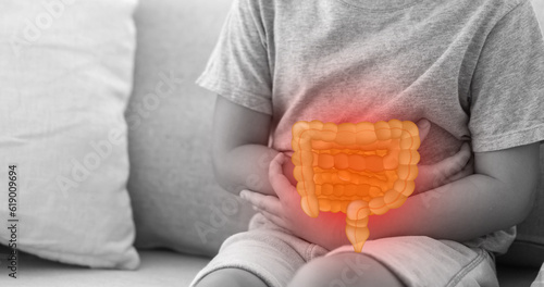 Portrait of sick unhappy little child asian boy touching belly stomach with suffering from stomach ache pain, gastritis, gastroenteritis, food poisoning, diarrhea, intestinal inflammation at home