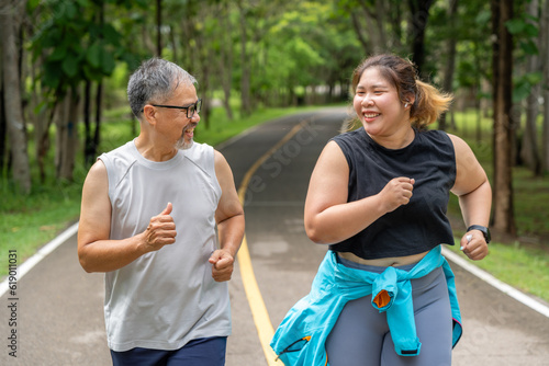 Happy middle age man and young overweight woman enjoy talking to each other during their morning run at running track of a local park
